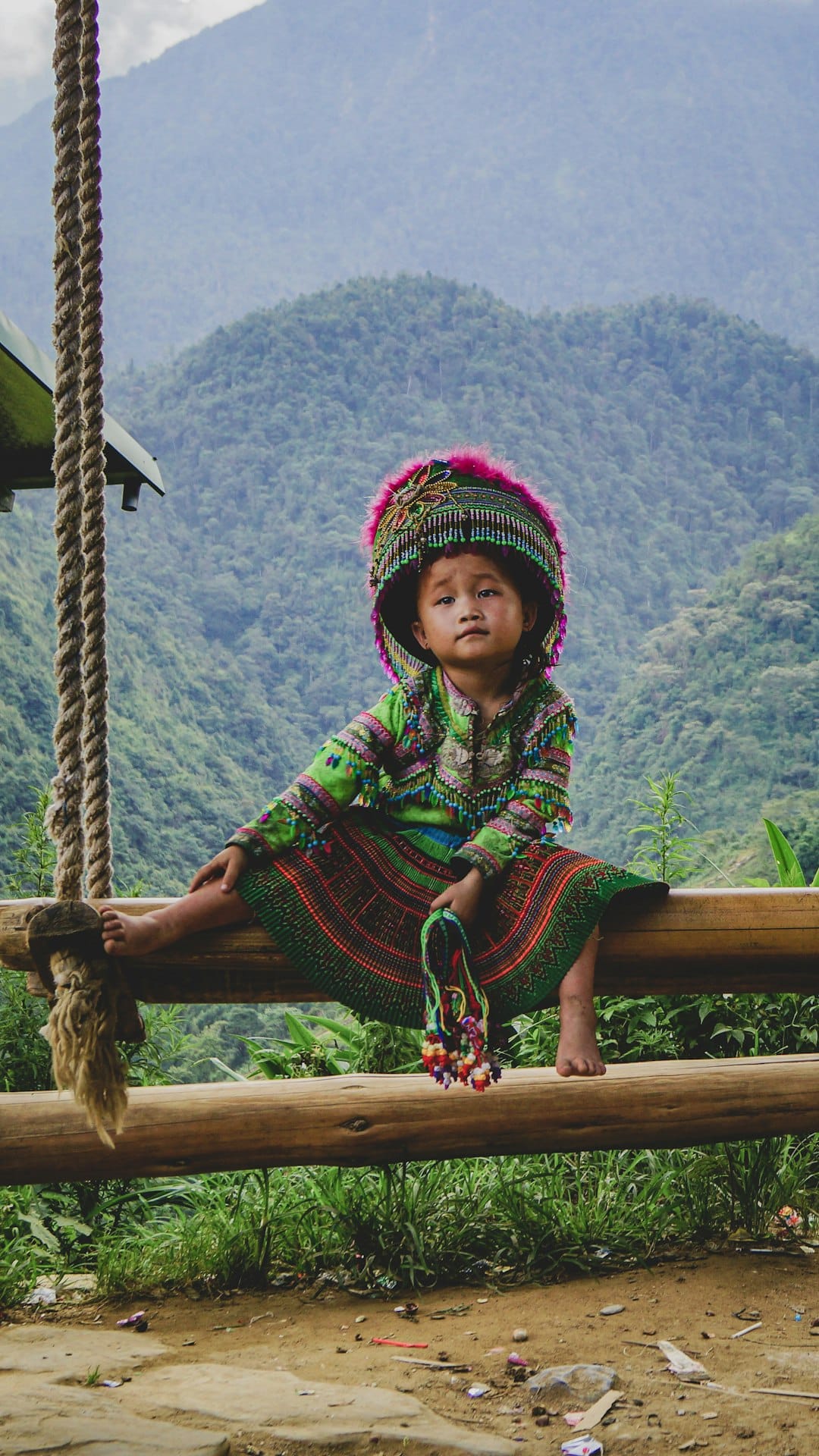 Photo by Kyle Petzer woman in green and red long sleeve dress sitting on brown wooden swing during daytime