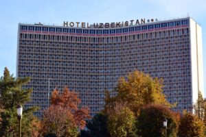 Facciata dell’Hotel Uzbekistan a Tashkent con alberi autunnali in primo piano – Viaggi Over 55