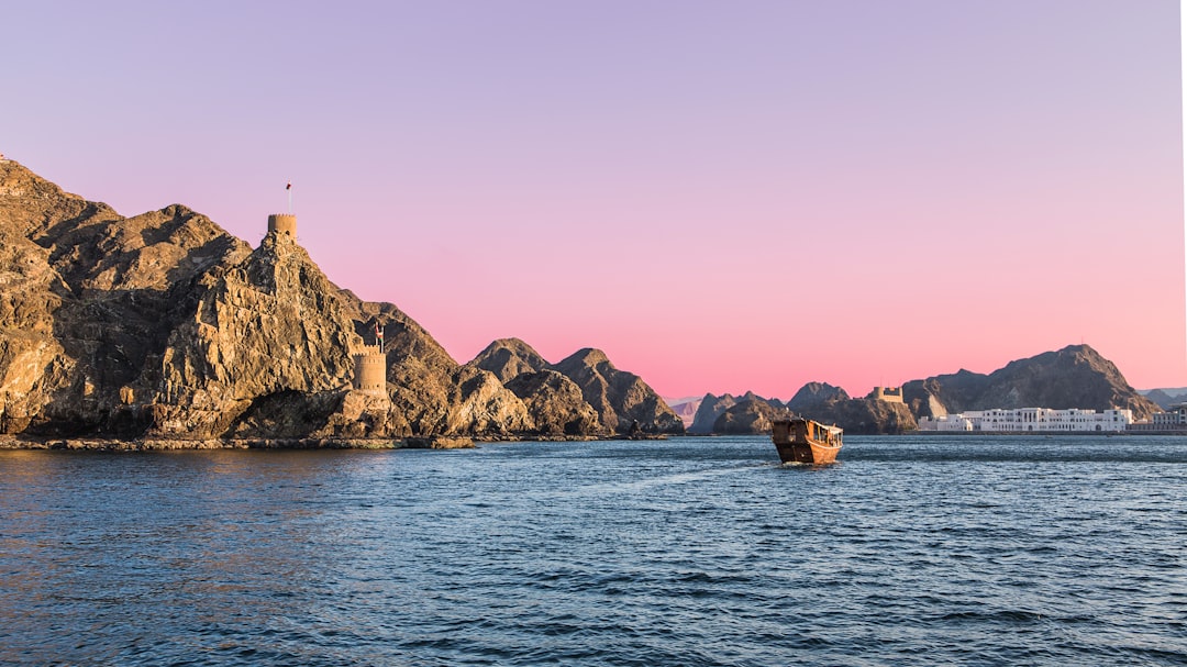 Photo by Lena Balk white and brown lighthouse on brown rock formation beside body of water during daytime