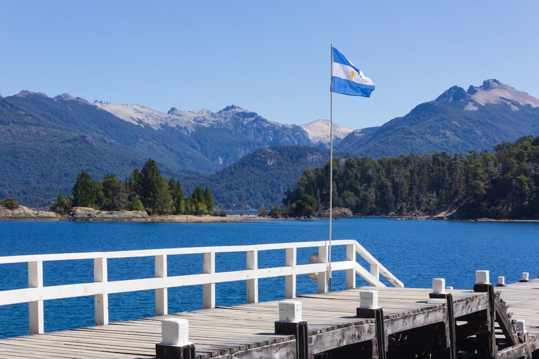 Photo by Fernando Távora white and blue flag on wooden dock near body of water during daytime