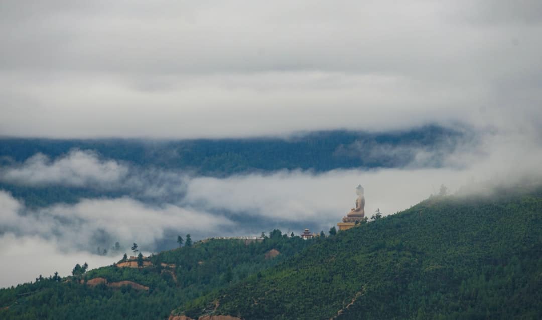 Photo by Pema Gyamtsho green mountain under white clouds during daytime