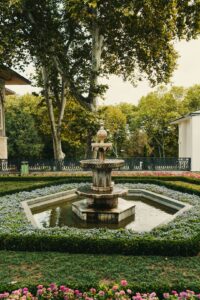 a fountain in a garden surrounded by flowers