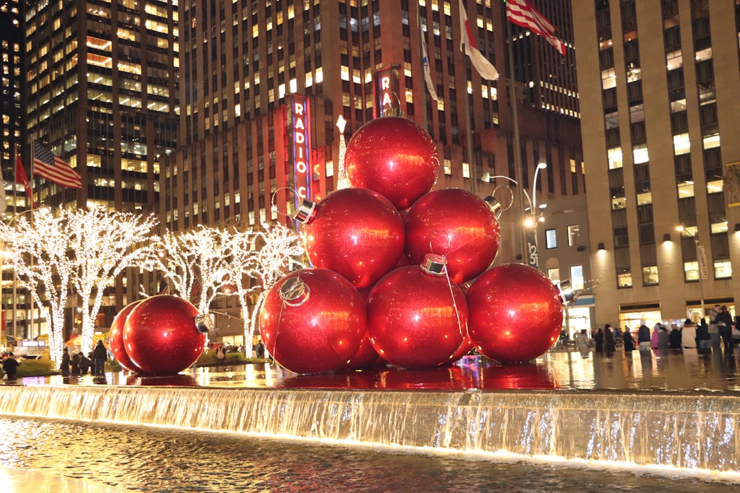 Photo by Jay Joshi a group of red balls sitting on top of a fountain