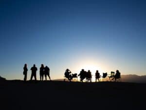 People gather outdoors, watching the sunset.