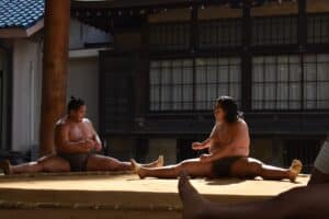 A group of people sitting on the ground in front of a building