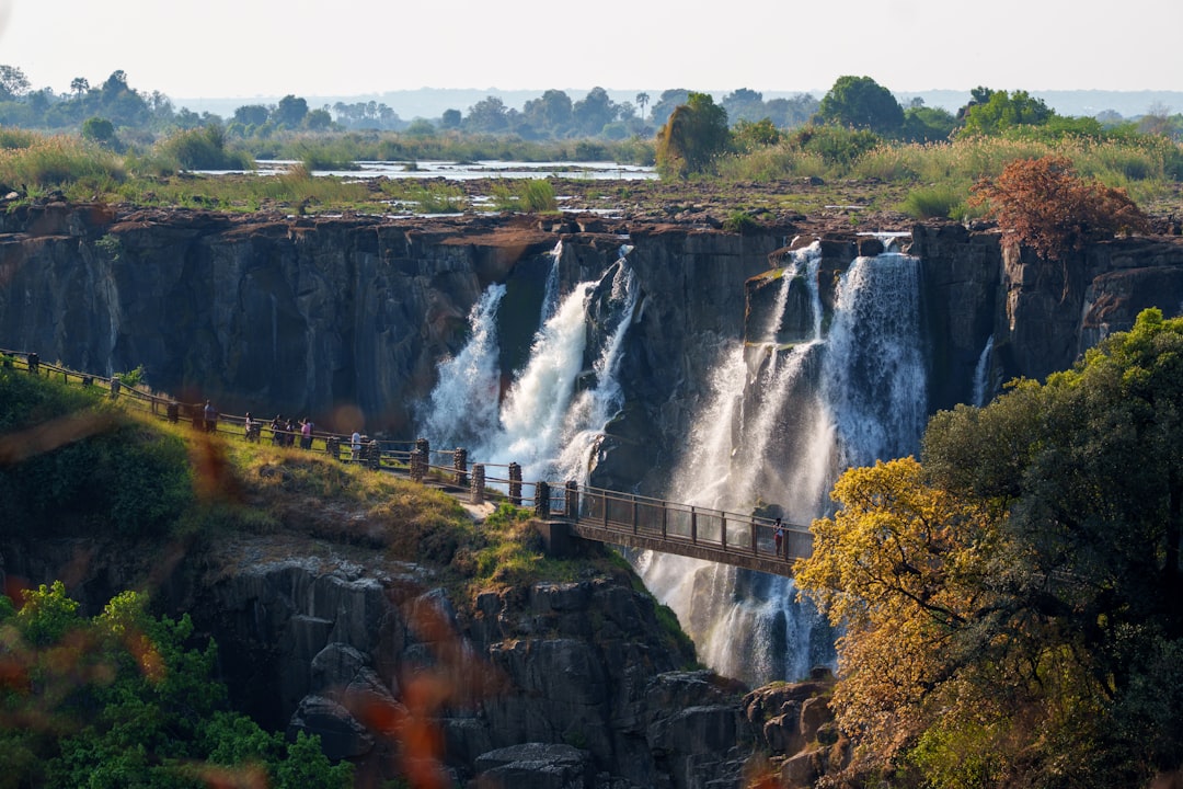 A scenic waterfall with a walking bridge over rocks.